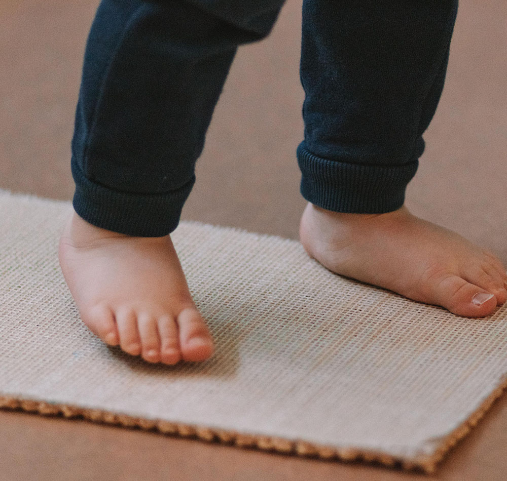 Kindliche Füße auf einem Teppich - erste Schritte wagen.