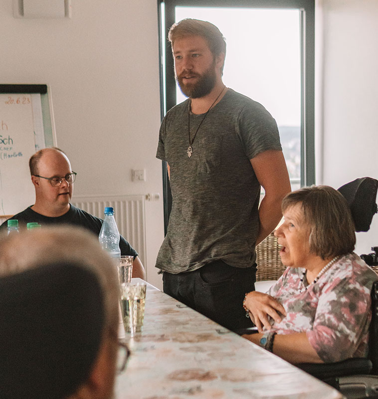 Workshop-Leiter spricht mit Teilnehmern im Rollstuhl