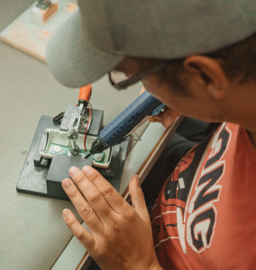 Mitarbeiter lötet elektronische Komponenten.