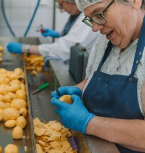 Mitarbeiterin schält Kartoffeln in der Großküche.