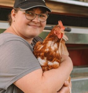 Mitarbeiterin hält liebevoll ein Huhn auf dem Bauernhof.