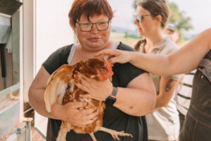 Eine Person hält liebevoll ein Huhn auf dem Hofgut Rocklinghausen.
