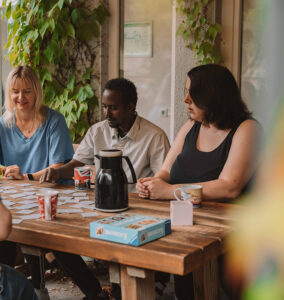 Freunde spielen Memory-Spiel an einem rustikalen Holztisch im Freien