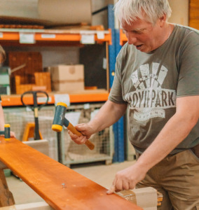 Mann arbeitet konzentriert an einem Holzwerkstück.