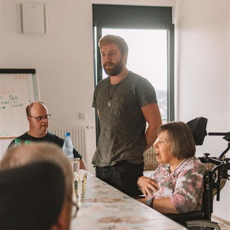 Workshop-Leiter spricht mit Teilnehmern im Rollstuhl